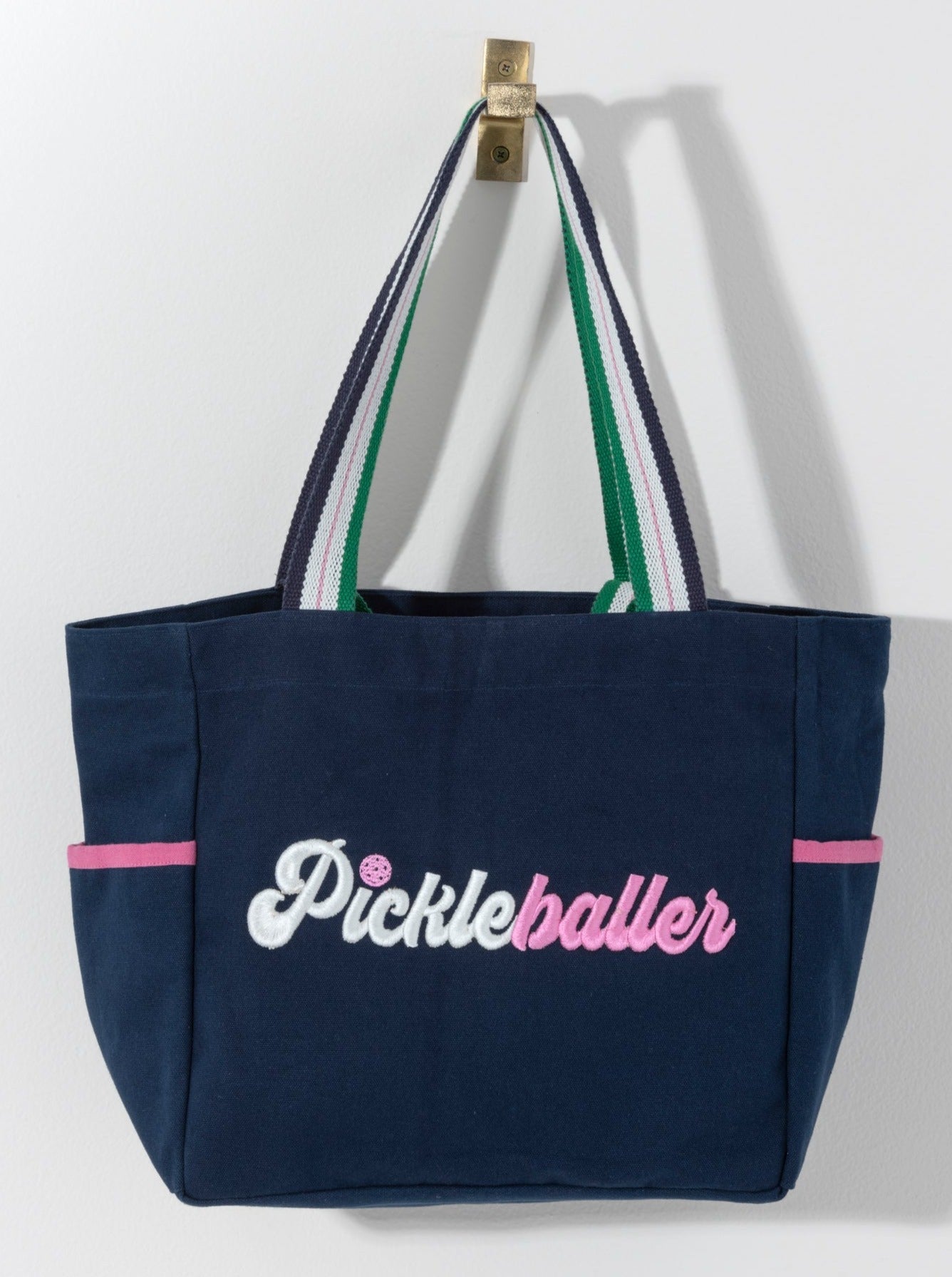 Stand out on the court with Shiraleah's "Pickleballer" Tote. Made from durable cotton canvas with multiple inner and outer pockets, you'll never leave an essential behind again. Whether you're a star player or just picking up on the trend, this is the perfect bag for the pickleballer in your life. Pair with other items from Shiraleah's Pickleball collection to complete your look!