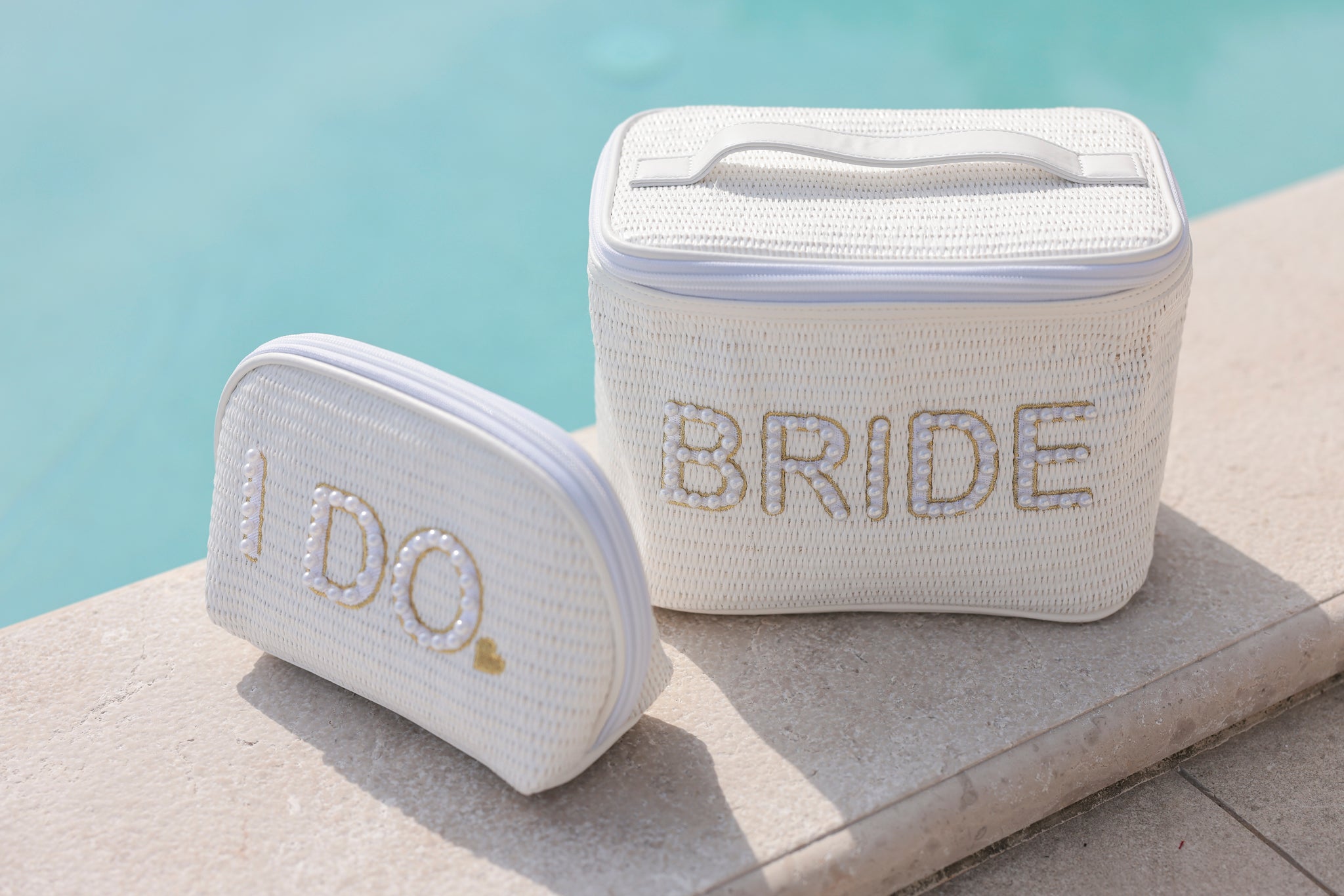 Carry all your cosmetic essentials for your big day in Shiraleah's "Bride" Cosmetic Case. This chic top-handle bag is embroidered with faux pearls and gold stitching and makes for the perfect makeup carrier for your honeymoon. Its woven white design matches the "I Do" Zip Pouch. Pair with other items from Shiraleah's Hitched collection to complete your look!
