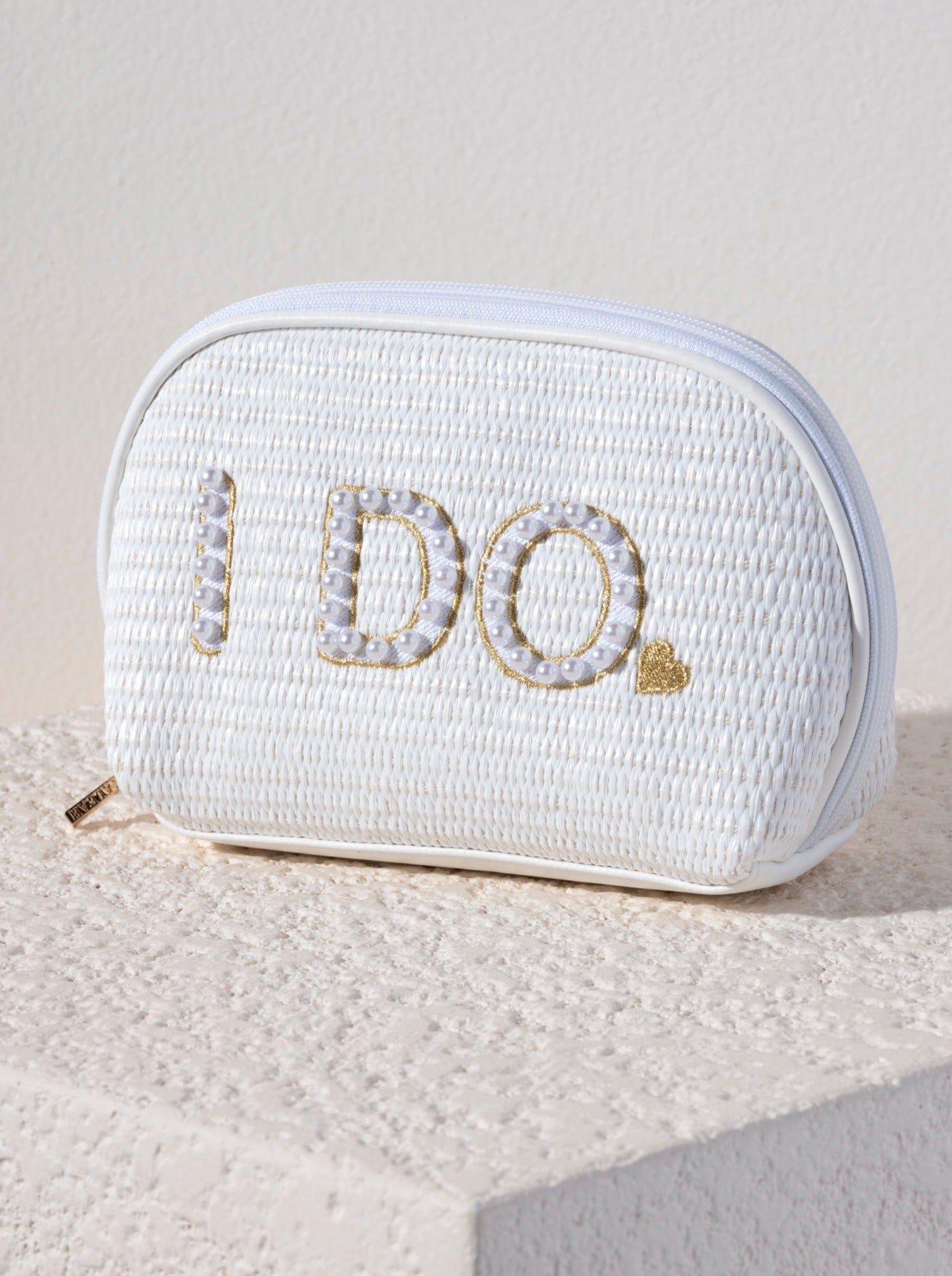 Carry all your cosmetic essentials for your big day in Shiraleah's "I Do" Zip Pouch. This chic top-zip pouch is embroidered with faux pearls and gold stitching and makes for the perfect cosmetic pouch for your honeymoon. Its woven white design matches the "Bride" Cosmetic Case. Pair with other items from Shiraleah's Hitched collection to complete your look!