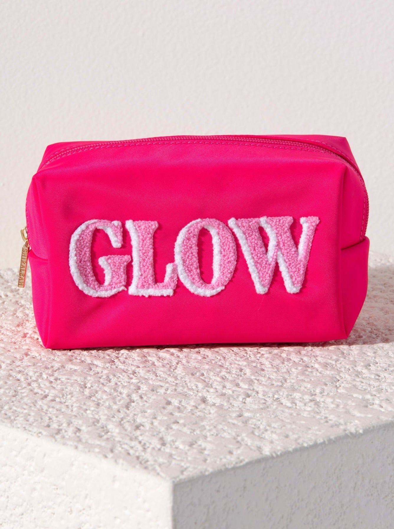 Carry all your odds and ends in style with Shiraleah's "Glow" Zip Pouch. Made of durable polyester in a vibrant pink, this rectangular case can fit inside of a larger zip pouch while still providing plenty of room inside. The trendy toothbrush embroidery spells the word "Glow" in light pink and white lettering. Pair with other items from Shiraleah to complete your look!
